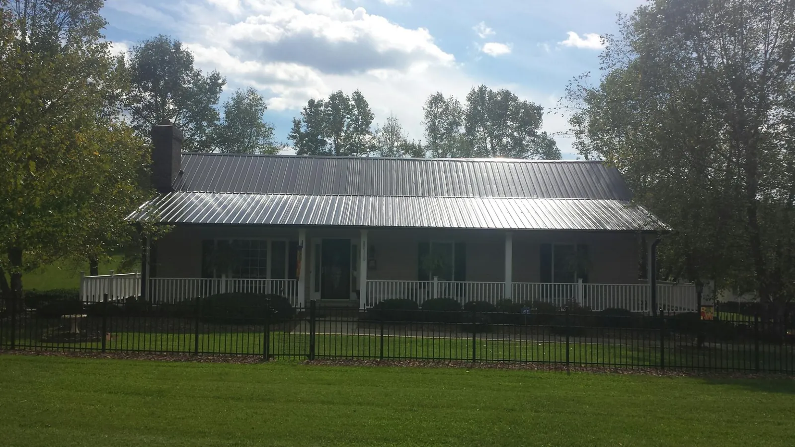 Gray metal roof on a brick ranch with a full width front porch — Gutter Guard Installation work by our crew in Ether