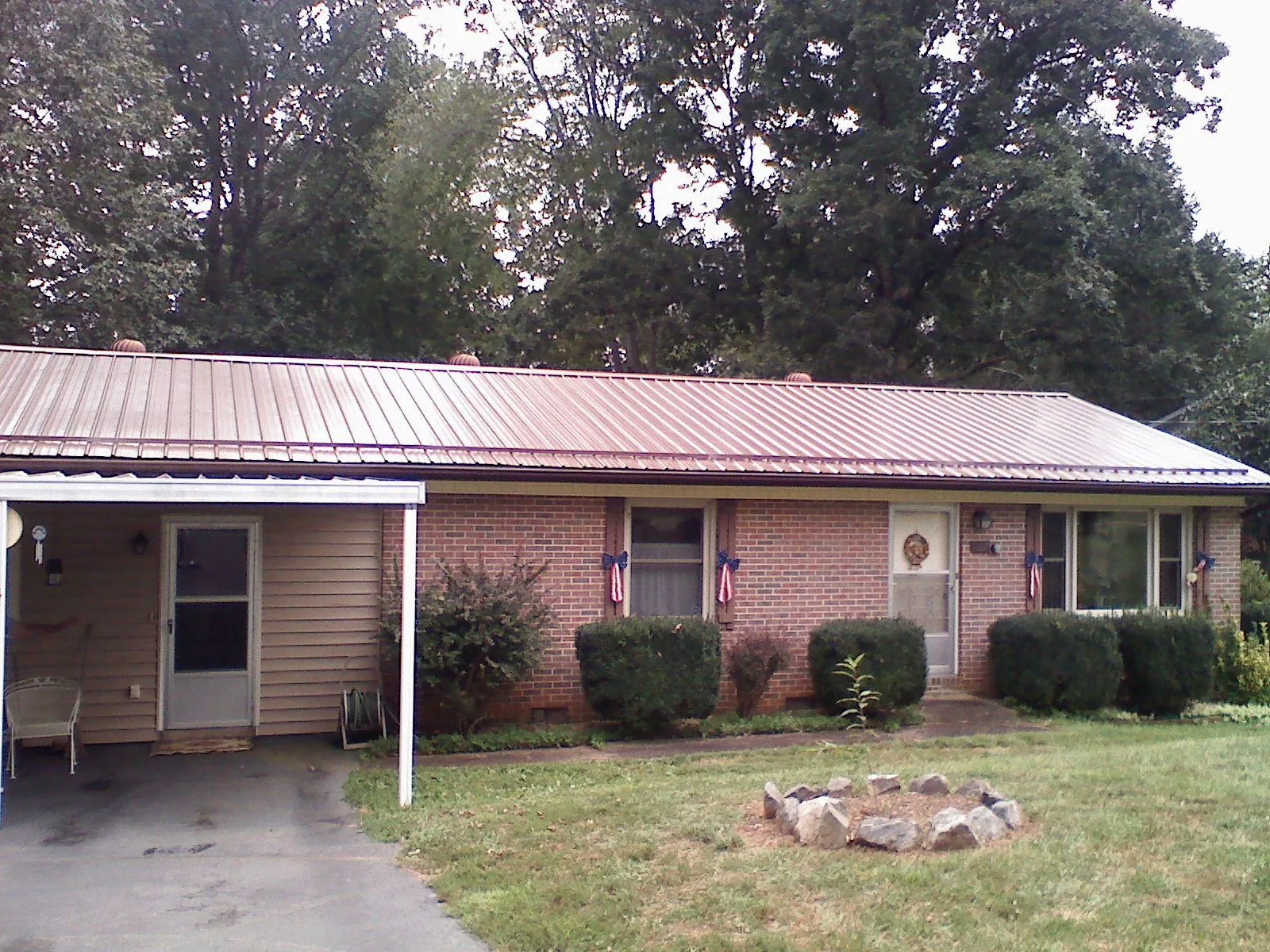Bronze metal roof and carport on a brick ranch home — Roof Repair work by our crew in Ether